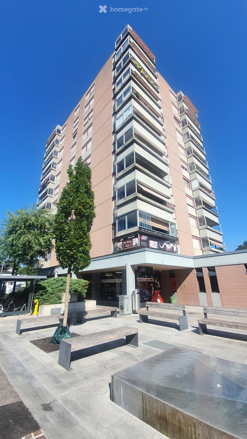 High-rise building with multiple floors, balconies, and a ground-level shop.
