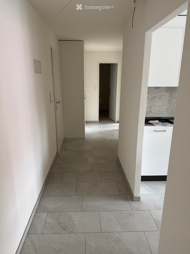 Empty hallway with tiled floor, white walls, and doors leading to other rooms.
