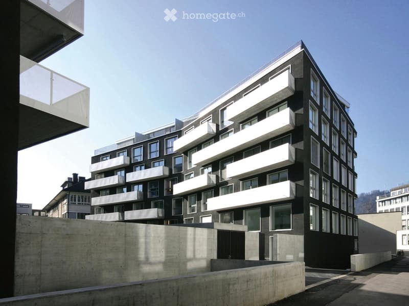 Modern multi-story building with black and white facade, large windows, and white balconies.