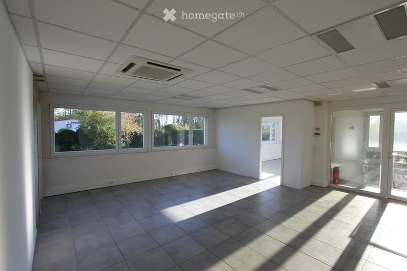 Empty room with white walls, tiled floor, large windows, and a glass door leading to an outdoor area.