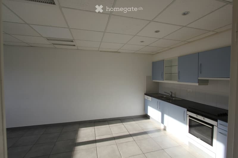 Modern kitchen with white cabinets, black countertops, and a stainless steel sink and faucet. The space is clean and well-lit with tiled flooring.