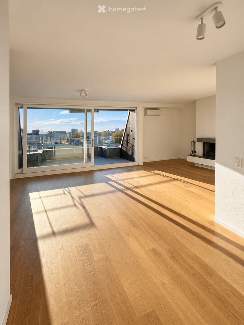 Empty room with wooden flooring, large sliding glass doors leading to a balcony, and a fireplace on the right side.
