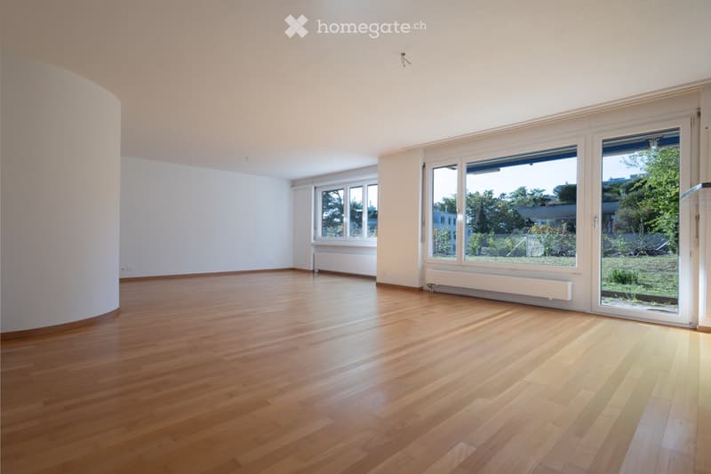 Empty room with wooden flooring, white walls, large windows, and a sliding glass door leading to an outdoor area.