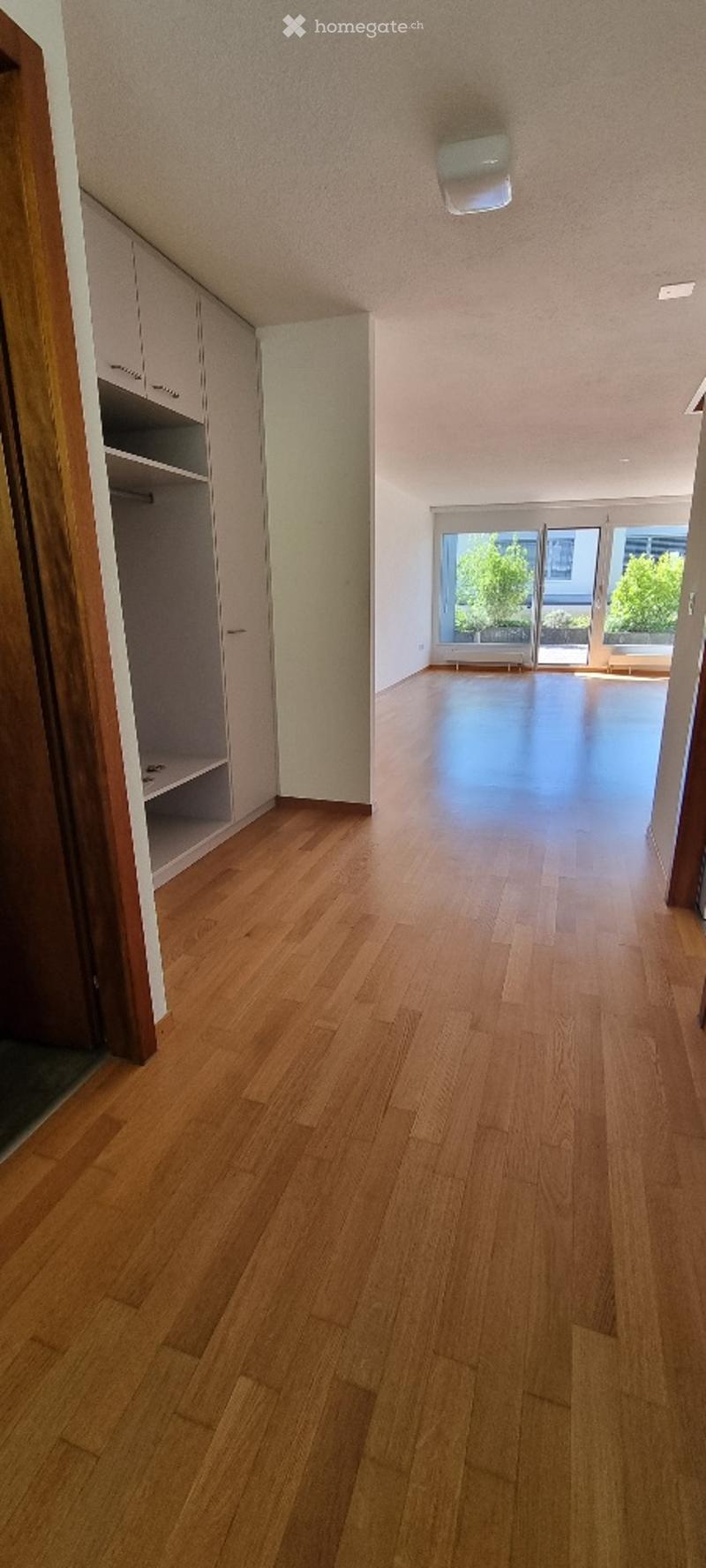 Empty room with wooden flooring, white walls, and built-in closet. Large sliding glass door leads to an outdoor area.