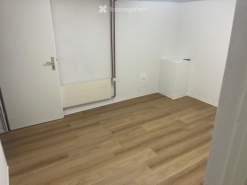 empty room, wooden floor, white walls, white door, white radiator, power outlet