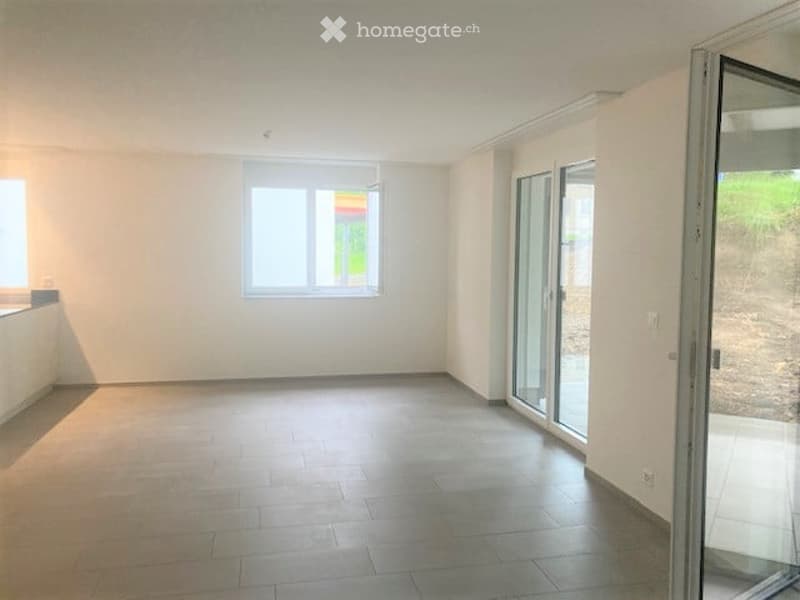 Empty room with tiled floor, white walls, large window, and glass sliding doors leading to an outdoor area.