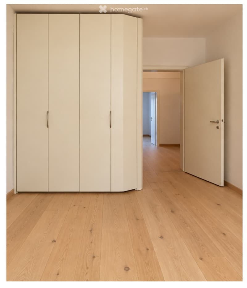 Empty room with light wooden flooring and a large built-in wardrobe. The room is unfurnished, with no visible furniture or equipment.