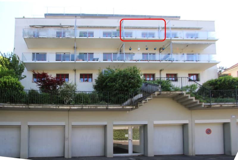 Multi-story residential building with balconies, garage, and staircase leading to upper levels.