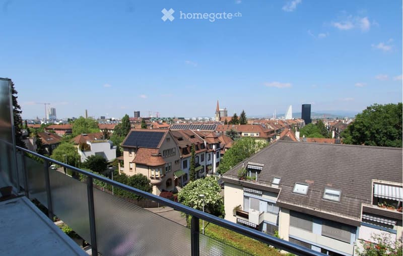 Balcony overlooking a cityscape with residential buildings, trees, and distant skyline.