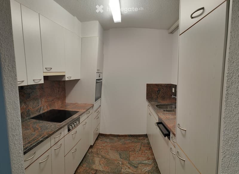 Modern kitchen with white cabinets, granite countertops, and stainless steel appliances including a stove, oven, and sink.