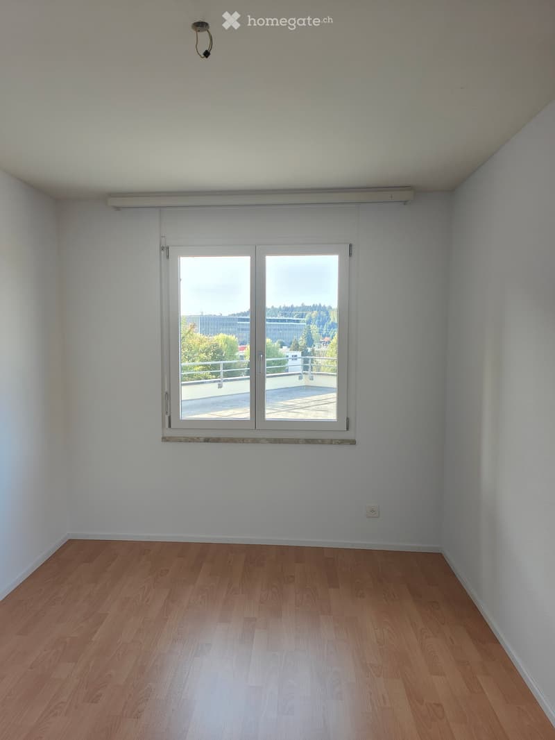 Empty room with wooden flooring, white walls, and a large sliding glass door leading to a balcony.