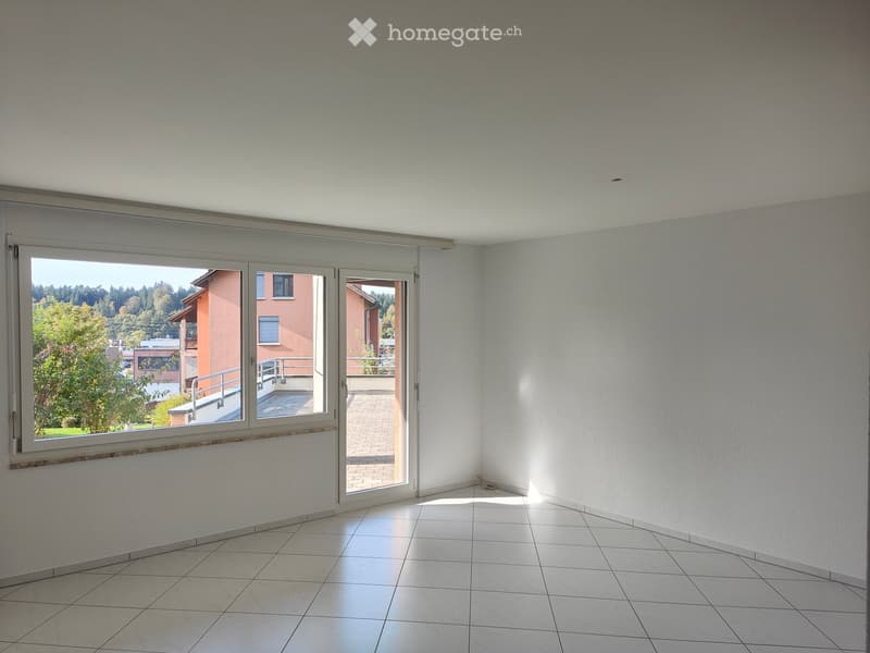 Empty room with white tiled flooring, large sliding glass doors leading to a balcony, and white walls.