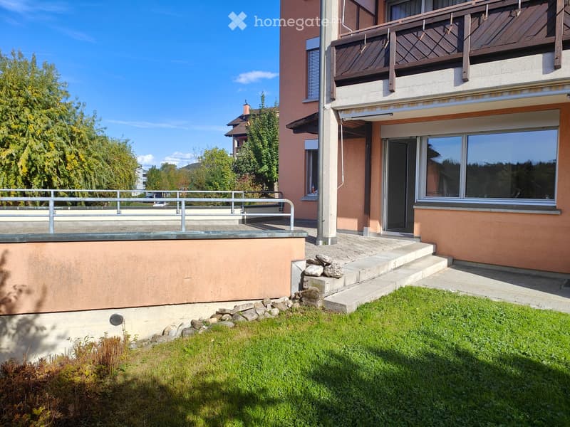 Two-story house with a balcony, raised ground floor, and well-maintained garden area.