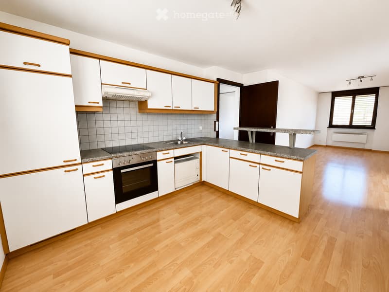 Modern kitchen with white cabinets, wooden accents, granite countertop, and stainless steel appliances including an oven and sink.