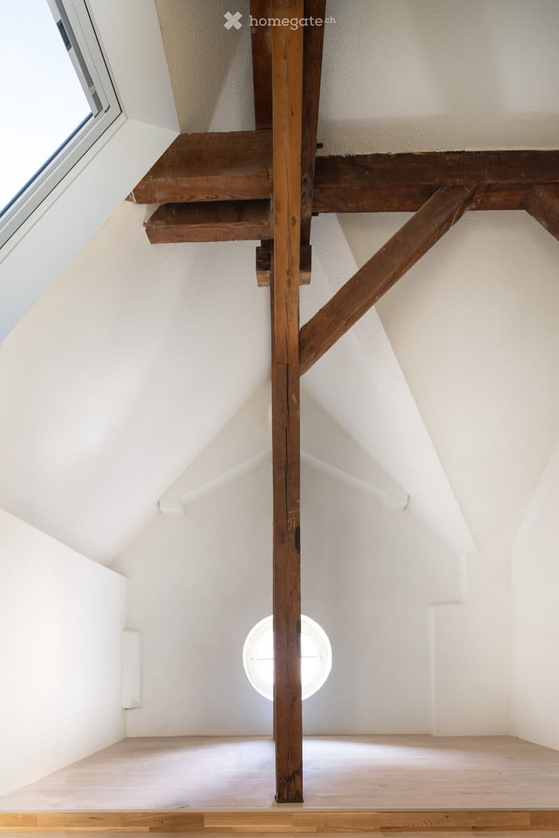 Empty room with wooden floor, white walls, and a staircase leading upwards. No furniture or equipment present.