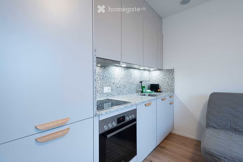 Modern kitchen with light blue cabinets, a built-in oven, a sink, and a countertop with a backsplash.