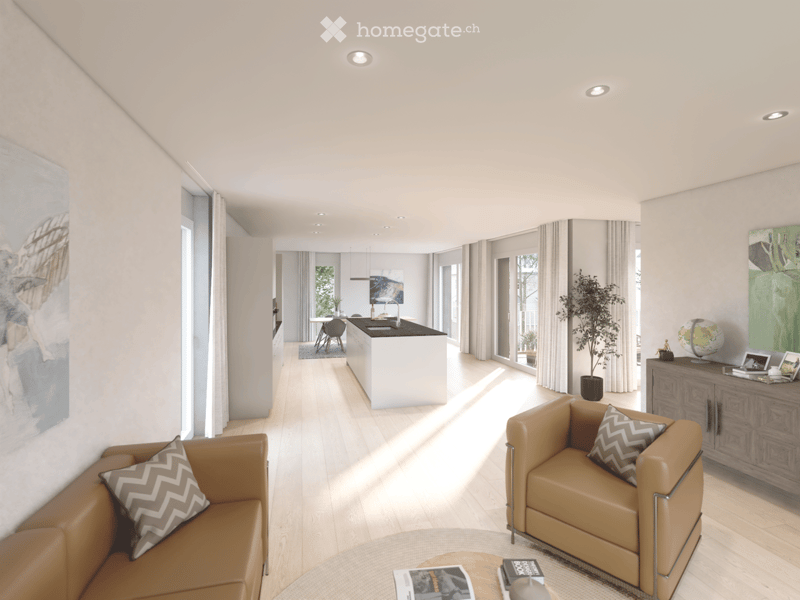 Modern living room with light wooden flooring, white walls, and large windows. Features a brown leather sofa, matching armchair, coffee table, and a kitchen area with a white island and bar stools.