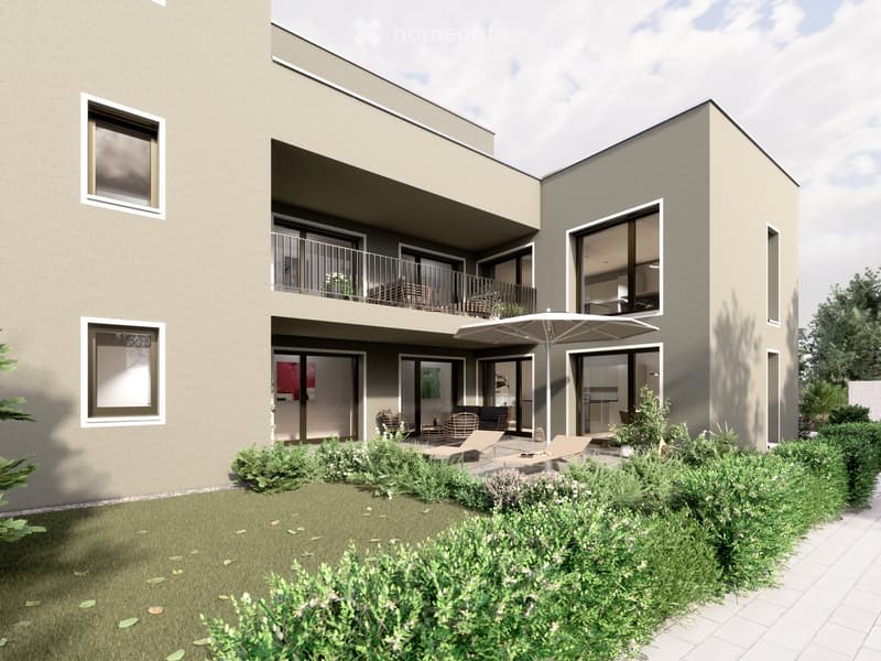 Modern two-story building with balconies, large windows, and a well-maintained garden area with lounge chairs and an umbrella.