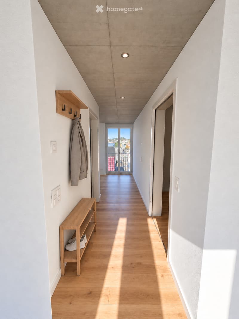 Modern hallway with light wooden flooring, white walls, built-in wooden shelves, coat rack, and a view to a balcony through large glass doors.