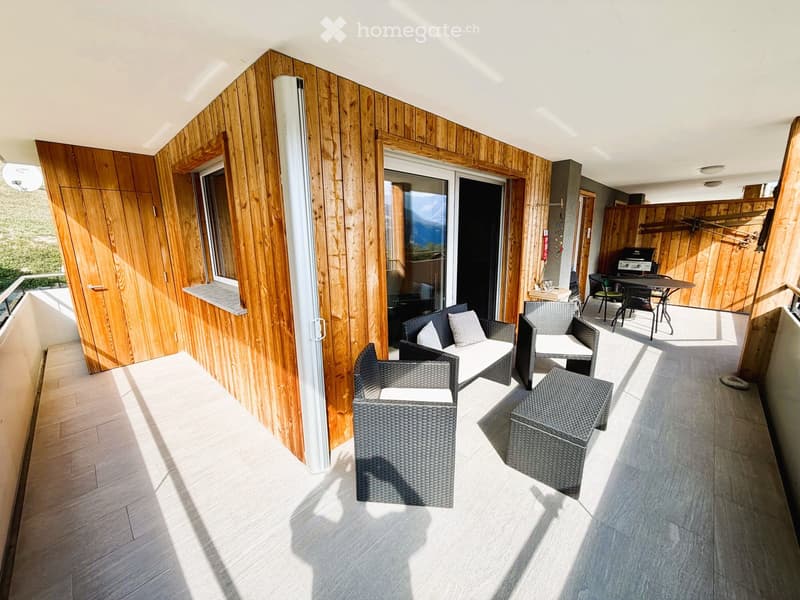Balcony with wooden walls, tiled floor, and outdoor furniture including a sofa, chairs, and a table.