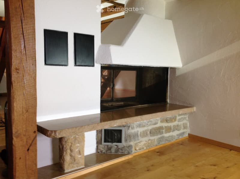 Hallway with a stone fireplace, wooden floor, and white walls.