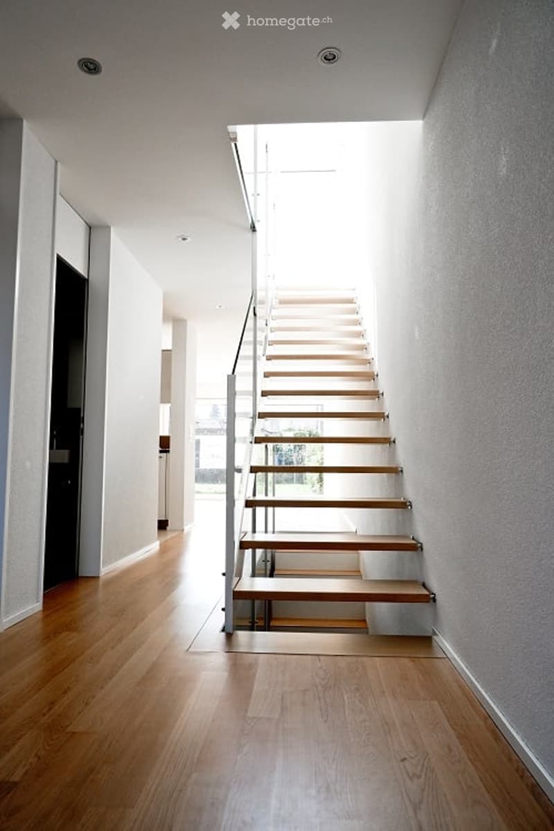 Open wooden stairs, white walls, glass railing
