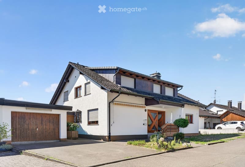 Two-story house with white exterior, dark roof, garage, and small garden area.