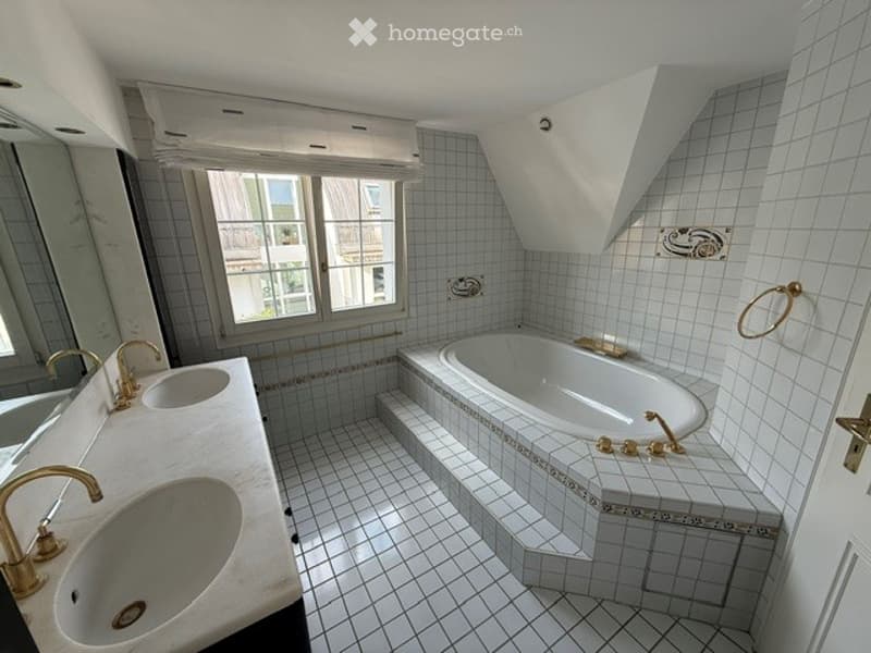Elegant bathroom with a large bathtub, double sink vanity, and decorative gold fixtures.