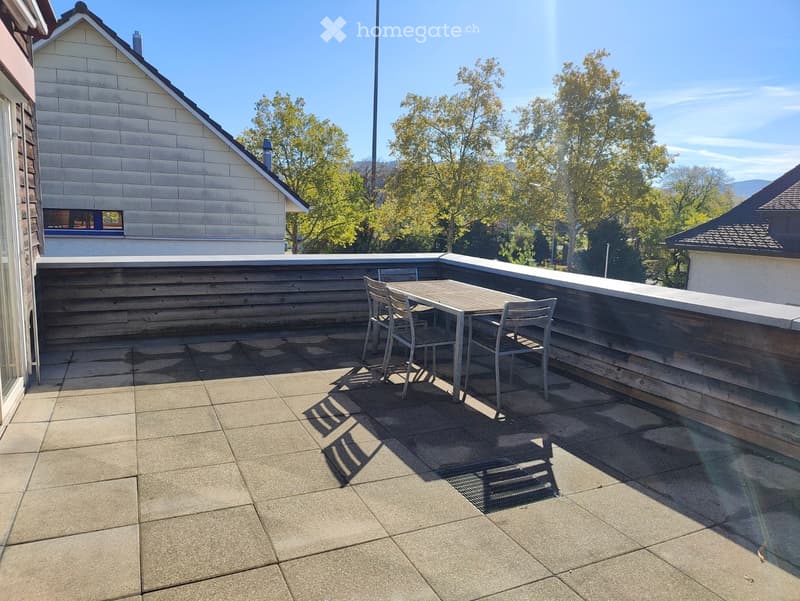 Balcony with a wooden railing, tiled floor, and a small table with chairs.