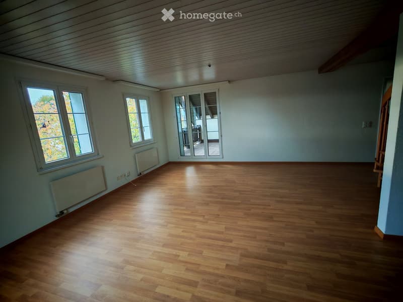 Empty room with wooden flooring, white walls, large windows, and a sliding glass door leading to a balcony.