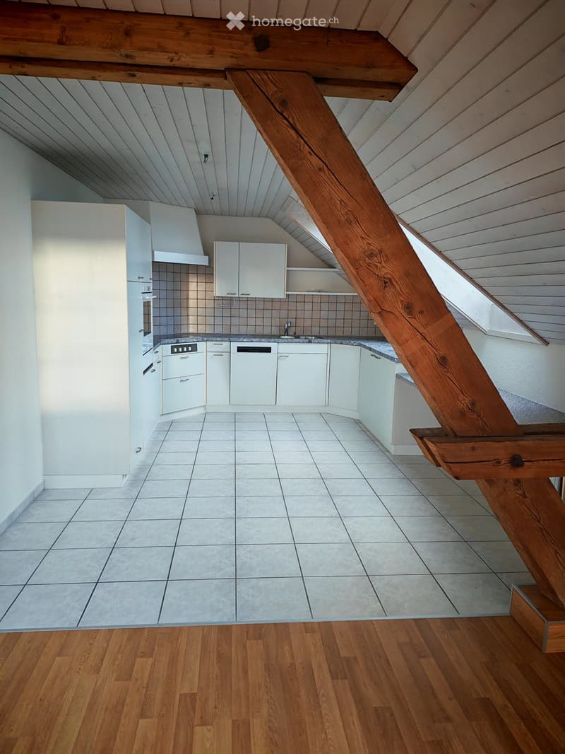 Modern kitchen with white cabinets, a sink, and a dishwasher, featuring a wooden staircase leading to an upper level.