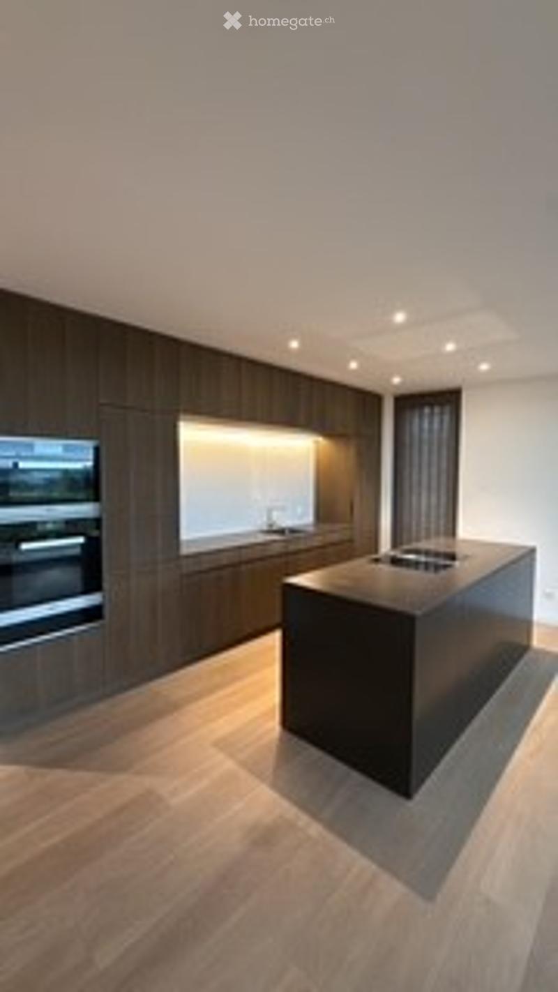 Modern kitchen with dark wood cabinetry, a central island, built-in appliances, and sleek design.