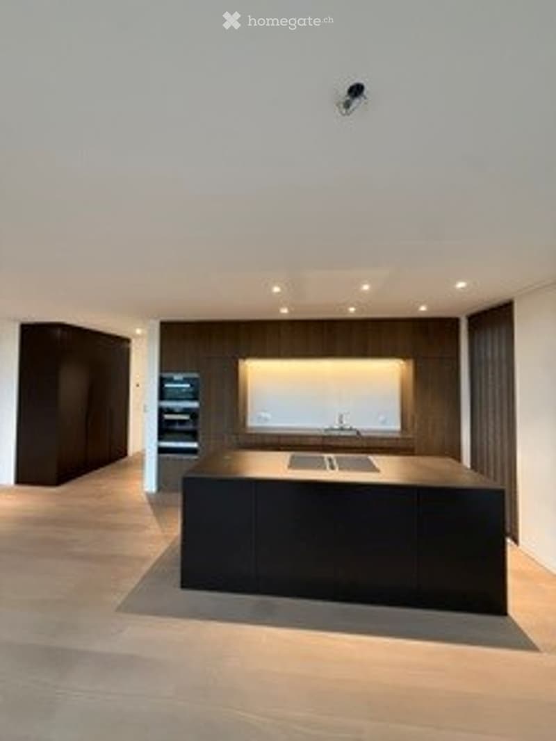 Modern kitchen with a large island, built-in oven and microwave, sleek countertops, and recessed lighting.