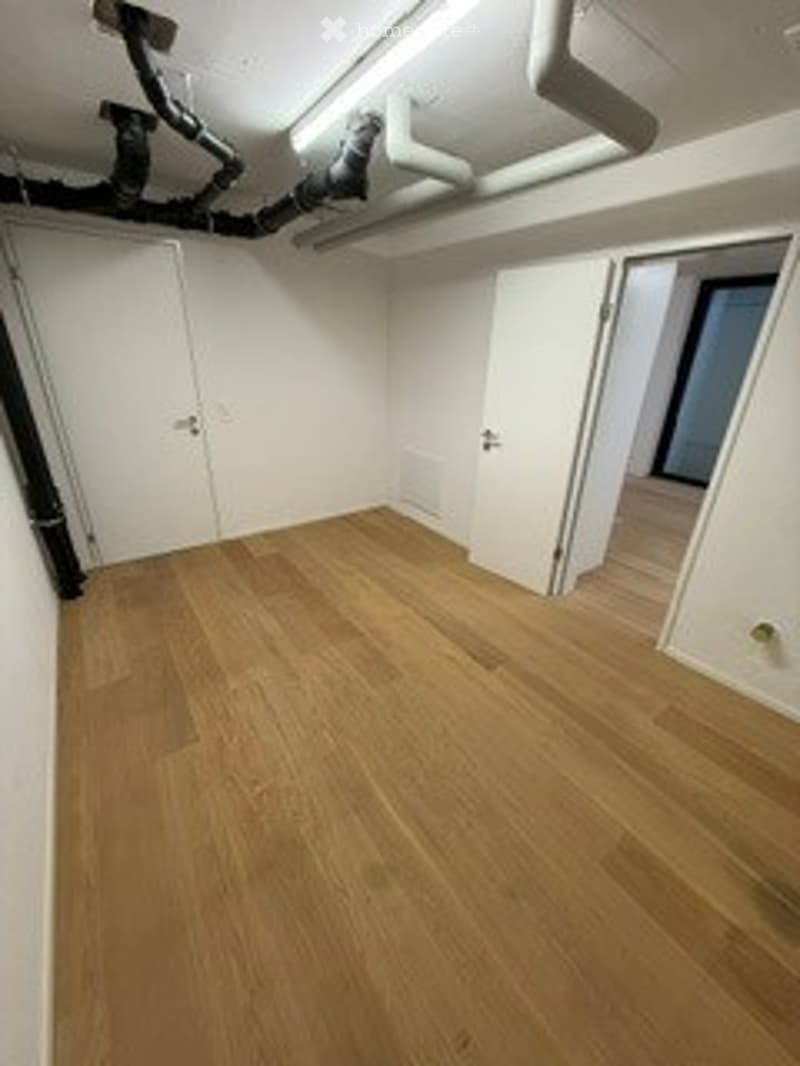 Empty room with light wooden flooring and white walls. No furniture or equipment present.