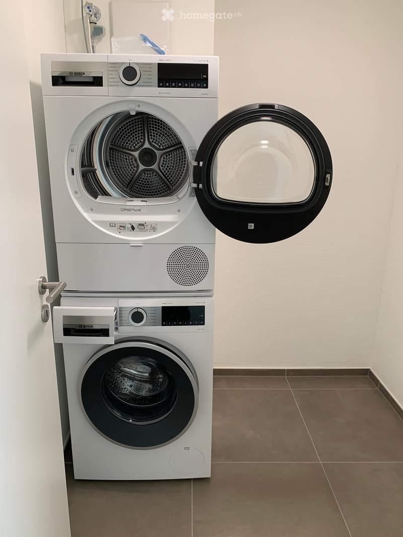 A modern Bosch washing machine and dryer unit with digital control panels, white finish, and open doors.