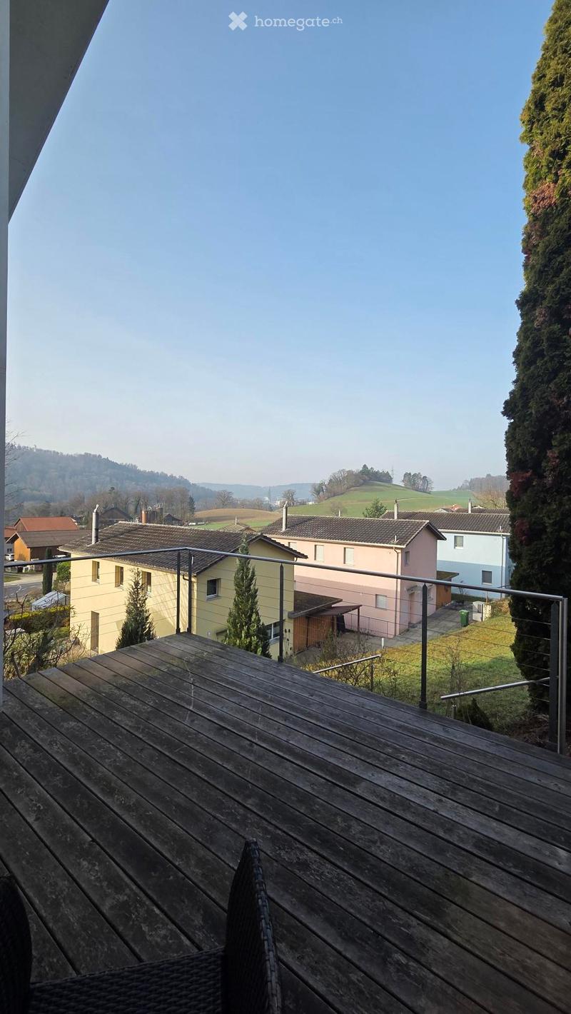 Modern apartment with balcony overlooking hills and fields in a rural area.