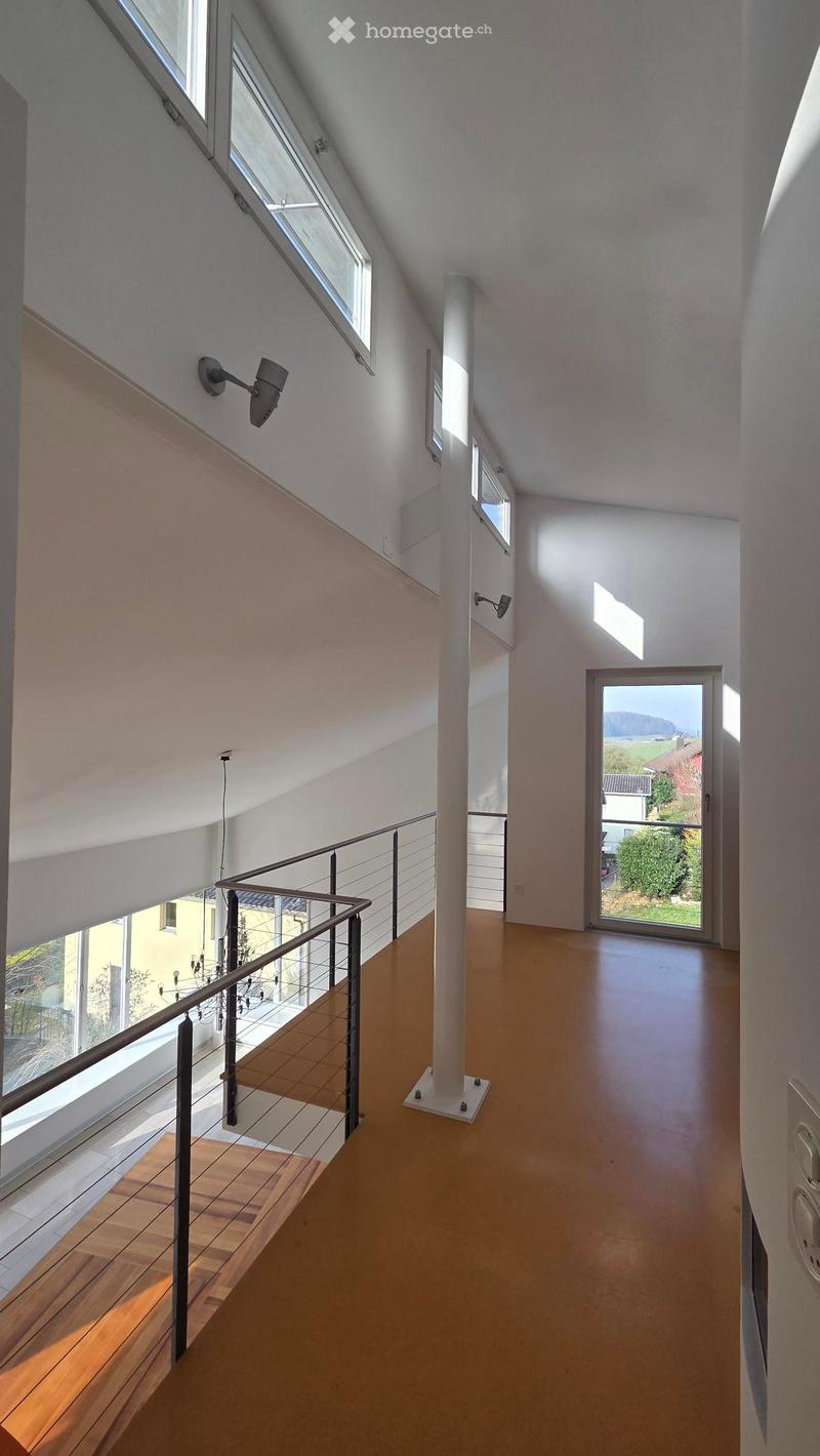 white walls, wooden flooring, open ceiling, balcony with metal railings, large windows, security lamps