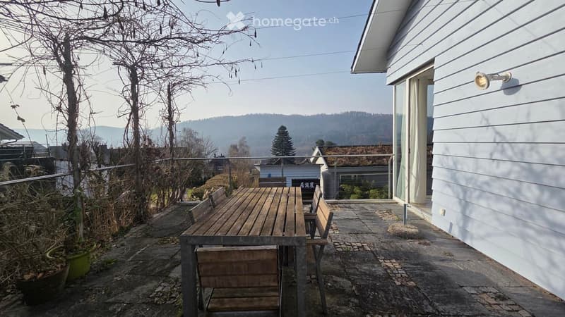 outdoor wooden table with chairs, fenced balcony, view of the hills