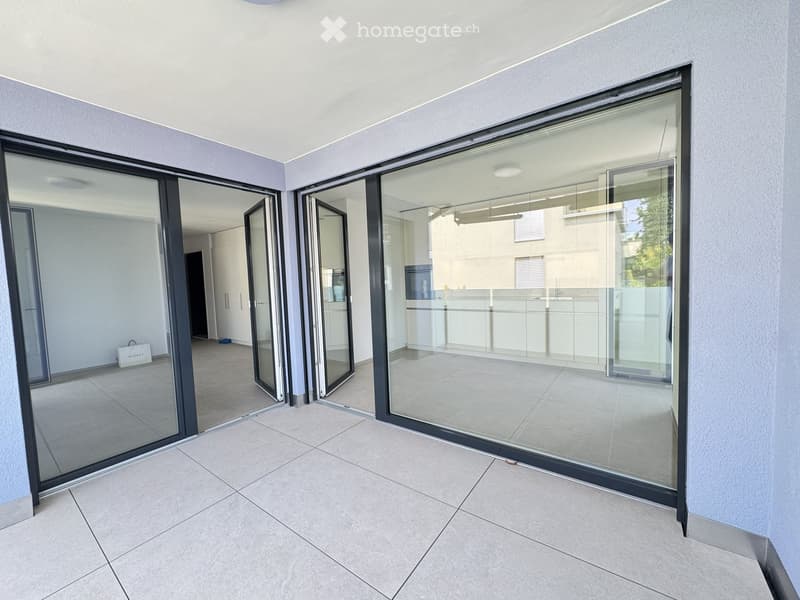 Empty room with large glass sliding doors, tiled floor, and light-colored walls.