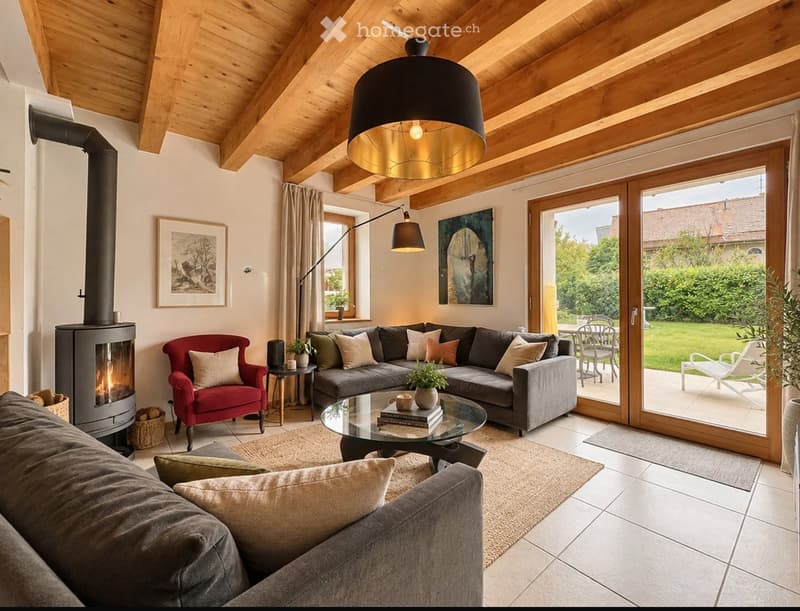 Modern living room with exposed wooden beams, a grey sectional sofa, a red armchair, a glass coffee table, a wood-burning fireplace, and large windows leading to a patio.