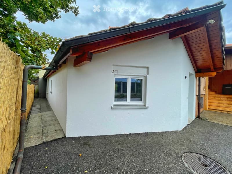 Single story house, white exterior walls, grey roof, glass window, bamboo fence, paved driveway
