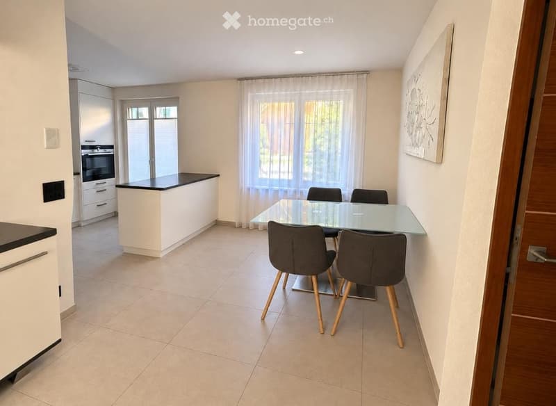 Modern kitchen and dining area with white cabinets, black countertops, a glass dining table with four chairs, and a large window with curtains.