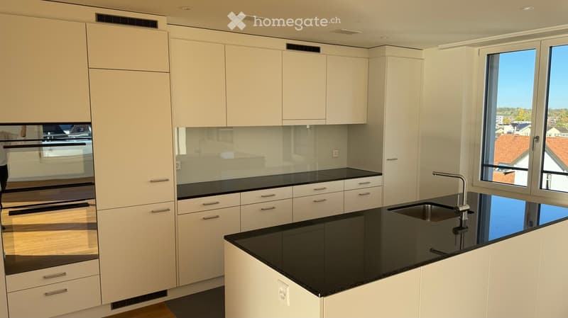 Modern kitchen with white cabinets, black countertops, and a stainless steel sink.