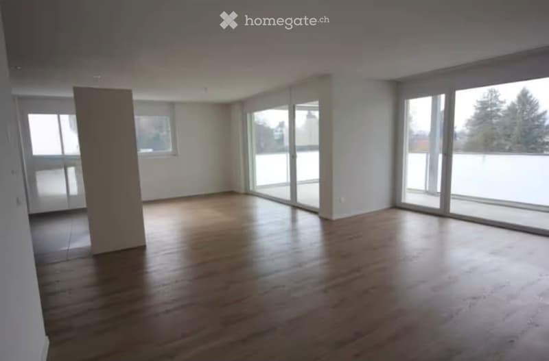 Completely empty room with wooden flooring, large windows, and sliding glass doors leading to an outdoor area.
