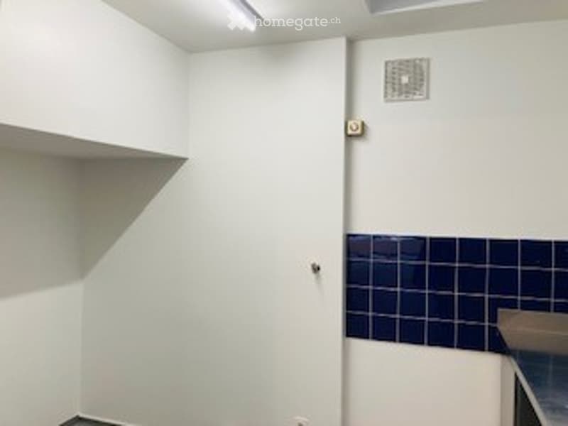Empty room with white walls, blue tiled section, and a closed door.