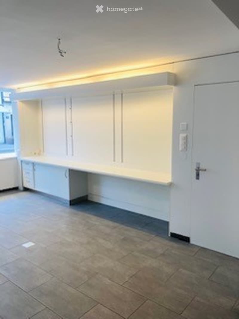 Empty room with white walls, tiled floor, built-in white cabinetry, and a closed white door.