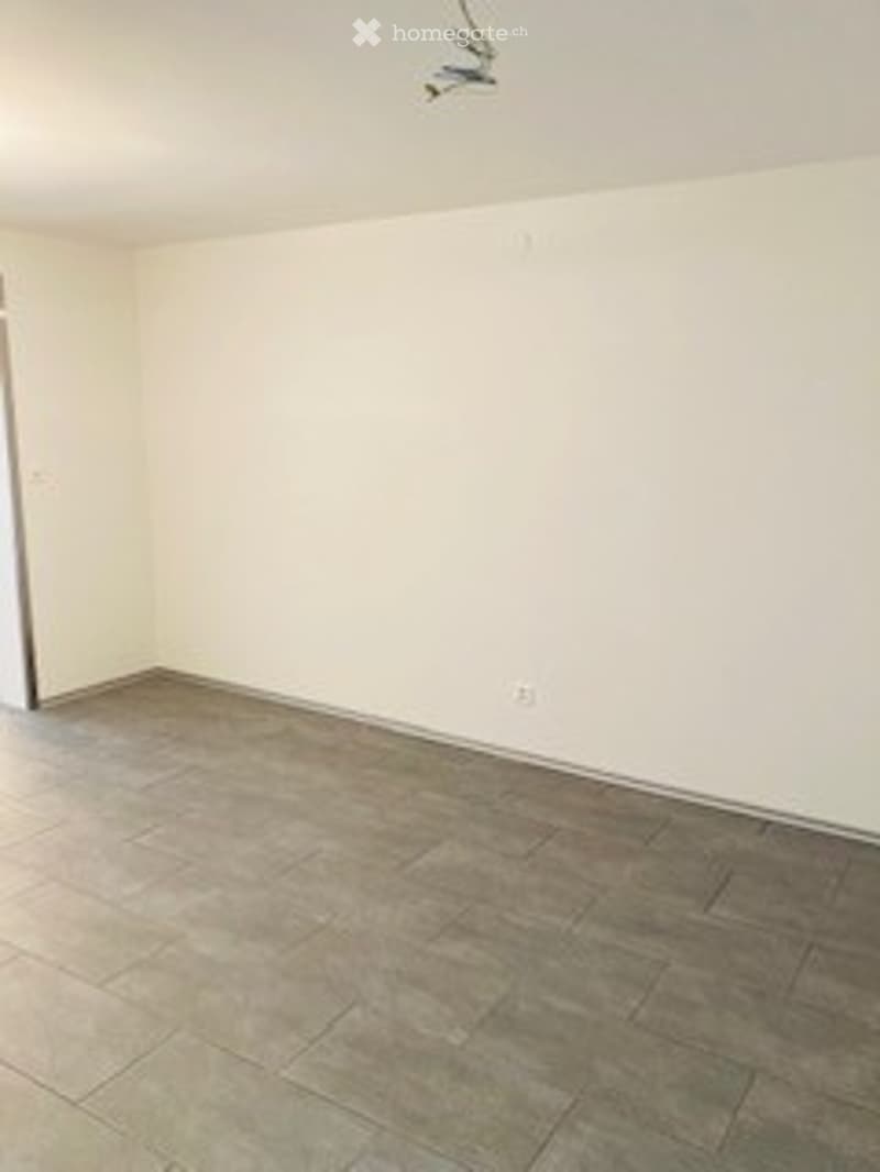 Empty room with beige walls, tiled floor, and a single door on the left side.