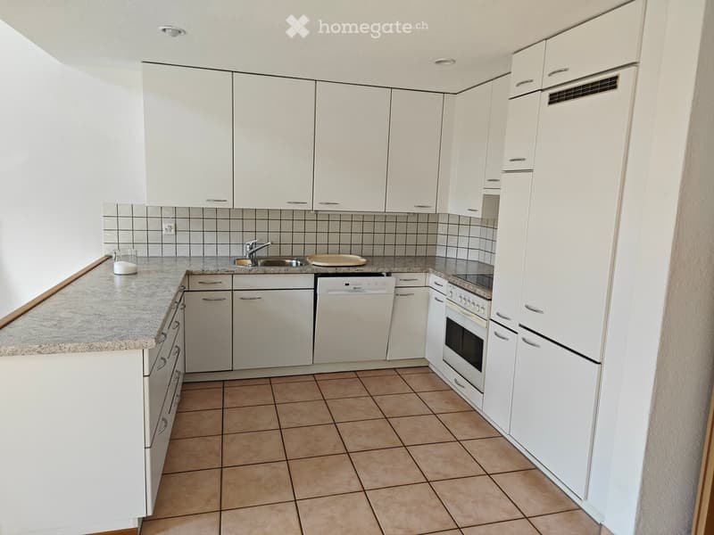 Modern kitchen with white cabinets, granite countertop, stainless steel sink, dishwasher, and oven. Beige tiled floor and backsplash.
