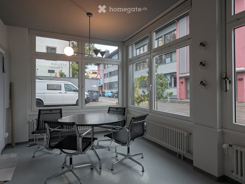Bright room with large windows, a round table, and four chairs, featuring a modern, minimalist design.