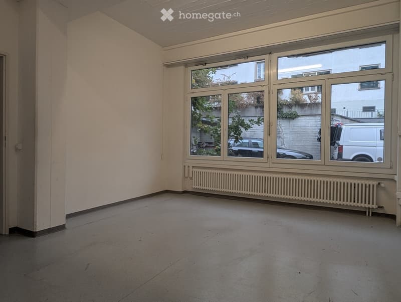 Empty room with large windows, radiator, and tiled floor.